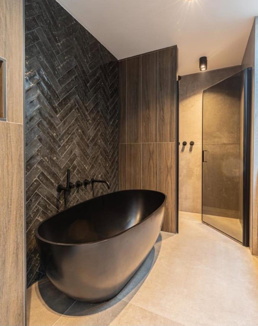 Herringbone leisteen tegelwand met zwart vrijstaand bad